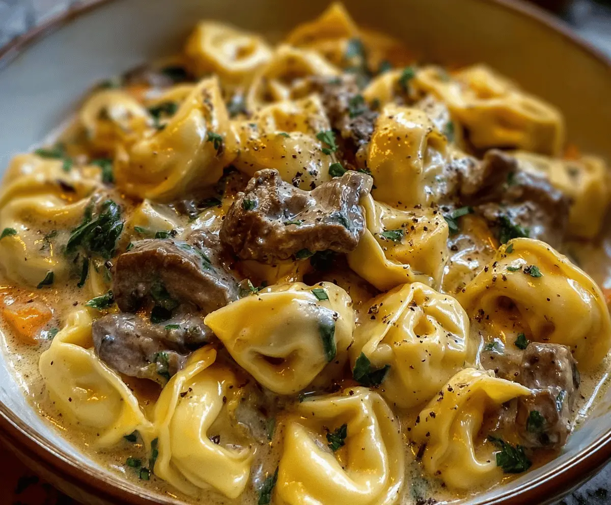 Creamy cheesesteak tortellini served in rich provolone cheese sauce, topped with melted cheese and fresh herbs.