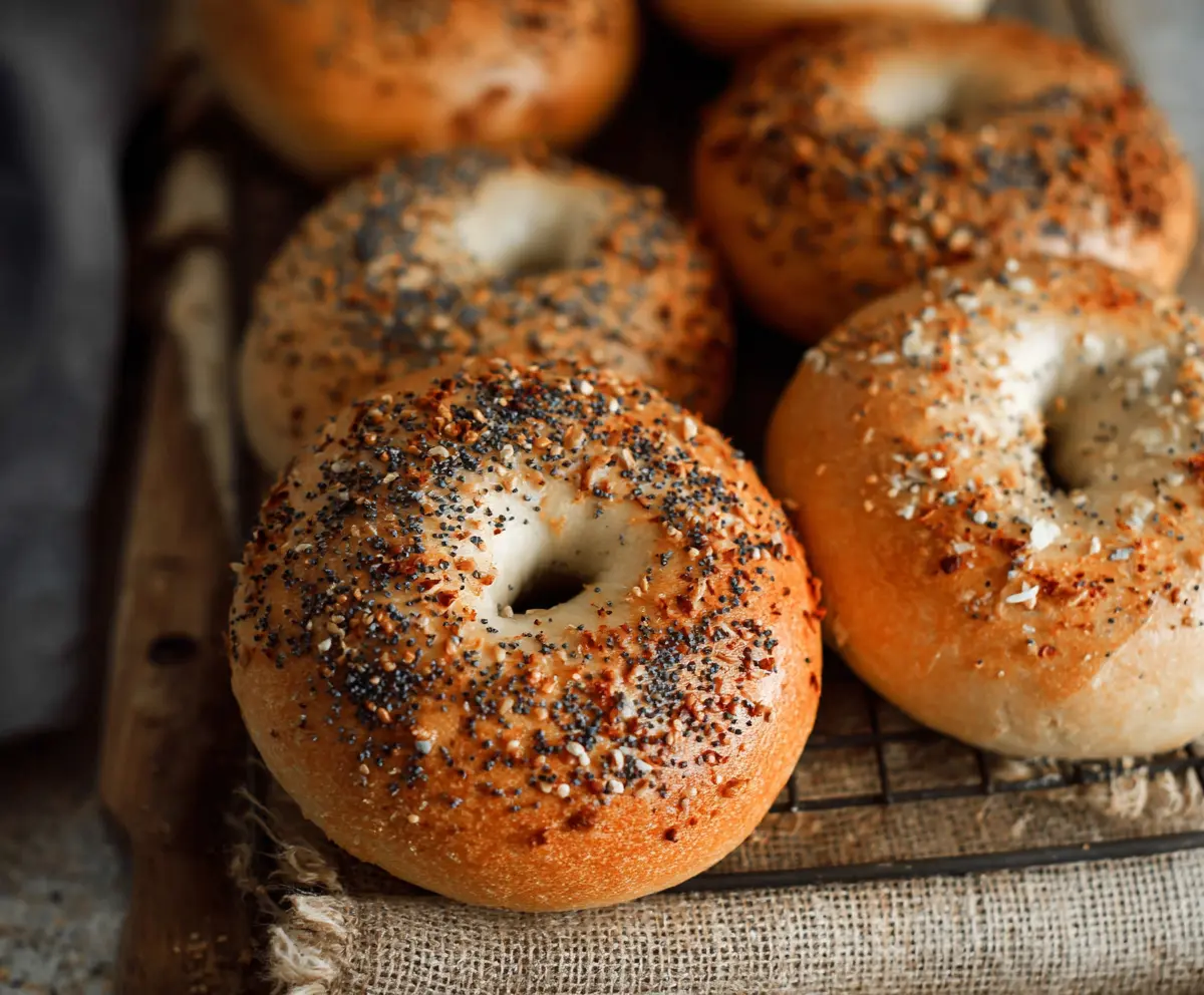 Golden-brown homemade sourdough bagels on a rustic wooden board